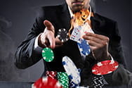 Ein Dealer hält brennende Spielkarten in der Hand und wirft Jetons. 